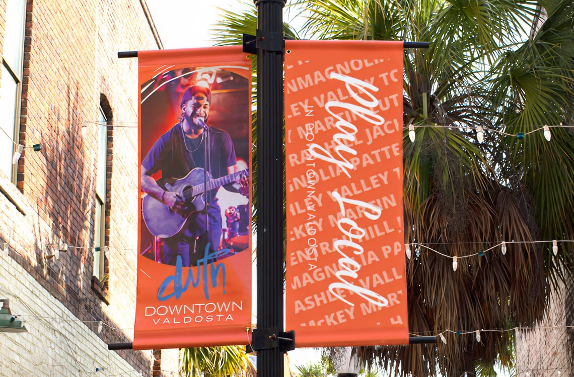 Orange pole banners on a black street light pole.